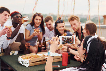 With delicious pizza. Group of young people in casual clothes have a party at rooftop together at daytime
