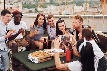 With delicious pizza. Group of young people in casual clothes have a party at rooftop together at daytime