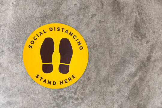 Top view footprint sign for stand in shopping mall, supermarket. Social distancing , COVID-19 comcept. Ccoronavirus crisis. yellow footprint sign with text caution social distance.