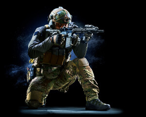 Army soldier in Protective Combat Uniform holding Special Operations Forces Combat Assault Rifle on dark background