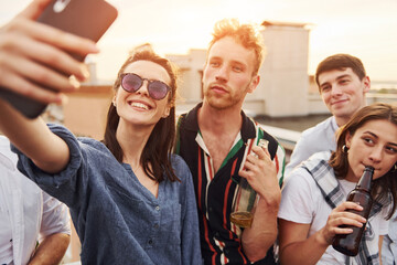 Taking selfie. Beautiful sunshine. Group of young people in casual clothes have a party at rooftop together at daytime