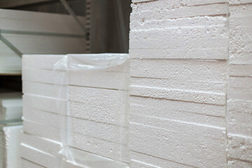 Stacks of expanded polystyrene in packaging at a building materials warehouse in a store. The insulation lies on metal racks in the distribution warehouse.