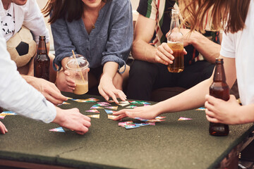 Playing game and sitting by the table. Group of young people in casual clothes have a party at...