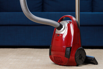 Red vacuum cleaner on a beige carpet