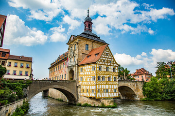Fototapeta na wymiar Bamberg, Germany - 7/6/2013: The Bamberg city hall sits on a island in the river Regnitz in downtown Bamberg, a UNESCO world heritage site