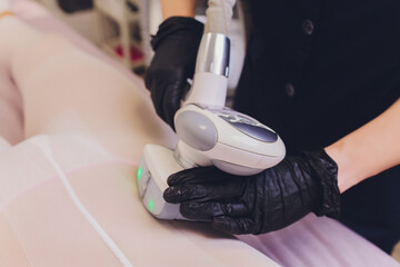Parts of female body in special white suit having anti cellulite massage with spa apparatus.