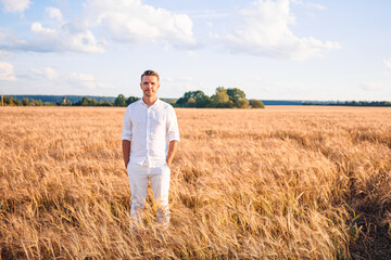 Naklejka na ściany i meble Happy tourist man in a wheat field