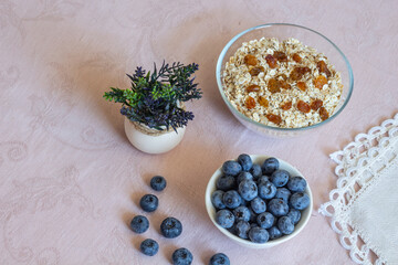 Bowls of granola, raisins,  and blueberries. Healthy breakfast every day. Copy space. Beige linen background. Flat lay