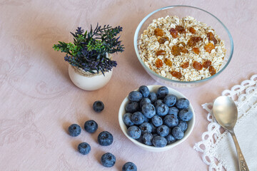 Bowls of granola, raisins,  and blueberries. Healthy breakfast every day. Copy space. Beige linen background. Flat lay