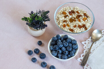Bowls of granola, raisins,  and blueberries. Healthy breakfast every day. Copy space. Beige linen background. Flat lay