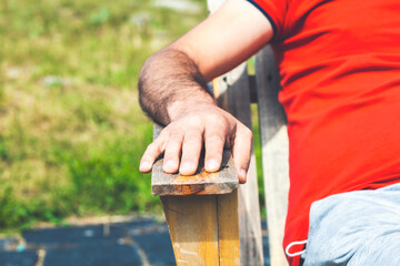 Picture of an young man’s hand in a  wooden chair