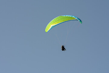 Persona vuela en parapente sobre el cielo azul
