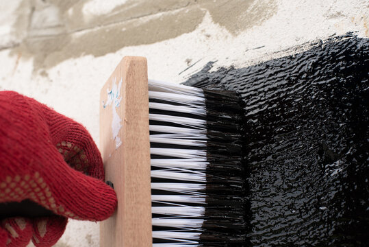 Roofer's hand in red mittens holding a brush