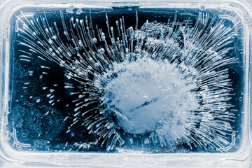 Pure transparent rectangular ice block with air bubbles on black background.