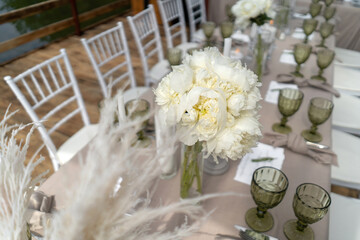 Decorated wedding table, white peonies and feathers. Chiavari chairs are at the table. Wonderful summer day.