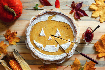 Delicious homemade pumpkin halloween pie with ash leaves and corn around. Sweet cake with sugar powder and cut piece top view. Food photography