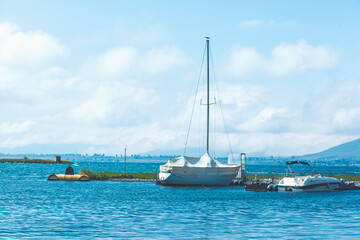 A lone sailboat is moored to a pier on a tranquil morning