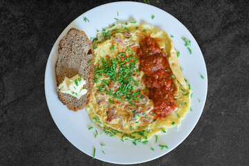Omelet with herbs and salsa and bread on plate from above 