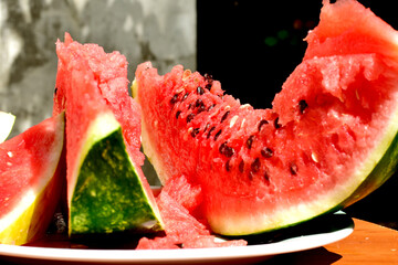 A snapshot of a ripe red watermelon cut into slices with black seeds.