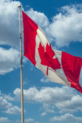 Maple leaf Flag of Canada against a background of blue sky with clouds