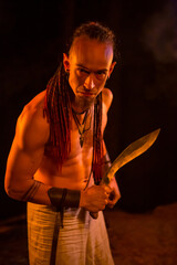 Irdorath group, clip making backstage. The caucasian man with dreadlocks,  with knife in the hand. Viking's nighttime in the forest is lighting by flamed torches.