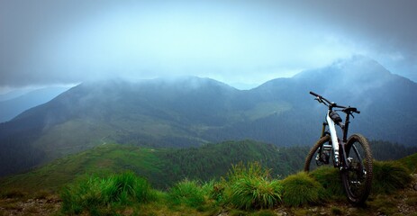 Fototapeta na wymiar Mountain Bike on the Mountain Cloudy Background. Mountain Bicycle Concept wallpaper