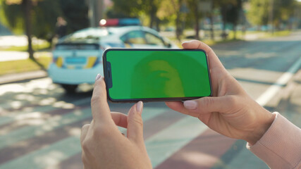 NEW YORK - 5 April 2018: Close up of woman hands holding and touching phone with green screen horizontal in the street people crosswalk background internet technology business message slow motion
