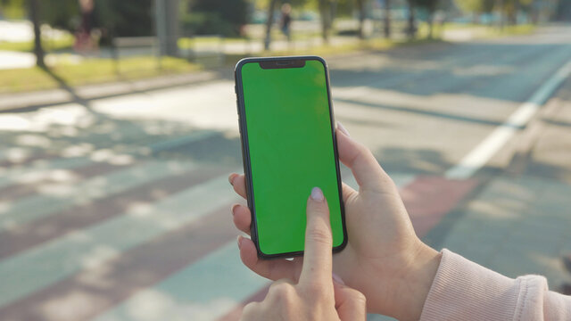 NEW YORK - 5 April 2018: Close up of woman hands holding and touching phone with green screen vertically in the street people crosswalk background internet technology business message slow motion
