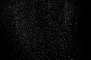 Abstract splashes of water on black background. Freeze motion of white particles. Rain, snow overlay texture.