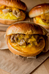 Breakfast sandwich. Bacon, fried egg, lettuce, tomato and onion on a bun being smashed by a waitresses hand. Action shot.