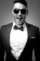 A young male brunette in a strict tuxedo suit with a bow tie. Black and white image