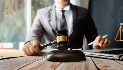 Justice and law concept.Male judge in a courtroom with the gavel, working with, computer and docking keyboard, eyeglasses, on table in morning light