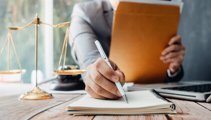 Justice and law concept.Male judge in a courtroom with the gavel, working with, computer and docking keyboard, eyeglasses, on table in morning light