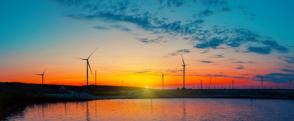 Panorama of wind farm by the sea at sunrise