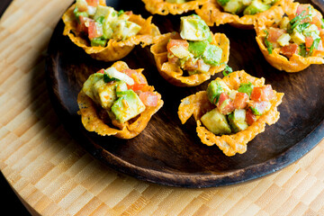 Spicy Guacamole served in crispy taco shells with salsas, cilantro and lime. Avocados diced and mixed with lemon and lime juices. Classic Tex-Mex, Mexican or American restaurant appetizer favorite.