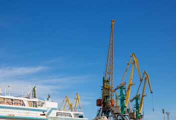 Fototapeta premium Yellow arrows of portal cranes against the blue sky. Place for the text