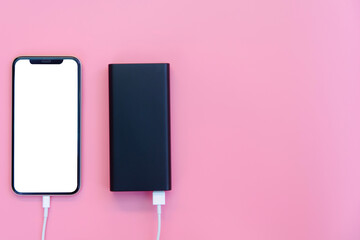 Smartphone charging with power bank on pink background. white screen or blank screen with clipping path for copy space. Flat lay