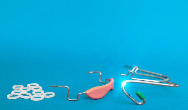 Orthodontic devices: removable metal braces and rubberized flesh-colored plastic cap,-for upper and lower teeth,dental rubber bands on light blue background.Selective focus on foreground.Copy space