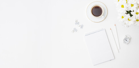 Mockup white notebook, white flowers, a cup of coffee on a white background