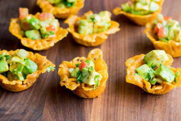 Spicy Guacamole served in crispy taco shells with salsas, cilantro and lime. Avocados diced and mixed with lemon and lime juices. Classic Tex-Mex, Mexican or American restaurant appetizer favorite.