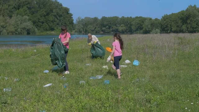 Family pick up garbage. A mother and children collect garbage on the banks of the river.