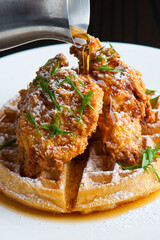 Chicken and waffles Classic American Diner Style Breakfast or Brunch menu item. Crispy homemade fried chicken on top of home buttermilk waffles topped with butter and maple syrup. 