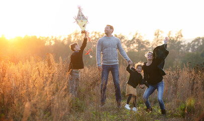 Beautiful young family with small children having fun in autumn nature.