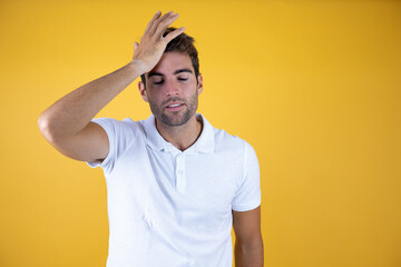 Young handsome man over yellow isolated background worried and stressed about a problem with hand on forehead, nervous and anxious for crisis