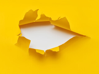 Big torn hole in yellow paper with a white background. Concept for placing text or other elements,...