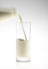 Bottle and Glass of Milk against White Background