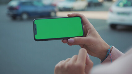 NEW YORK - 5 April 2018: Close up of woman hands holding and touching phone with green screen horizontal in the street sunlight car background internet technology business message slow motion
