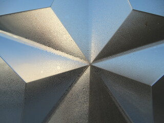 Geometric blue and grey glass surface with small water drops  - wet surfaces with sky light and shadow