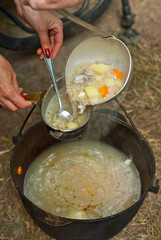 Fish soup is cooked on the fire. Ears in an iron bowl in nature.