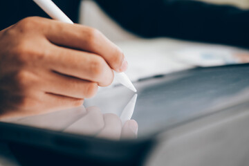 Close up businessman with stylus pen writing on digital tablet